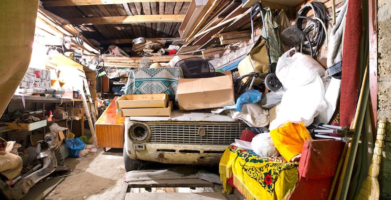 Garage inside. Old broken car, shelves with tools and stacks of things.