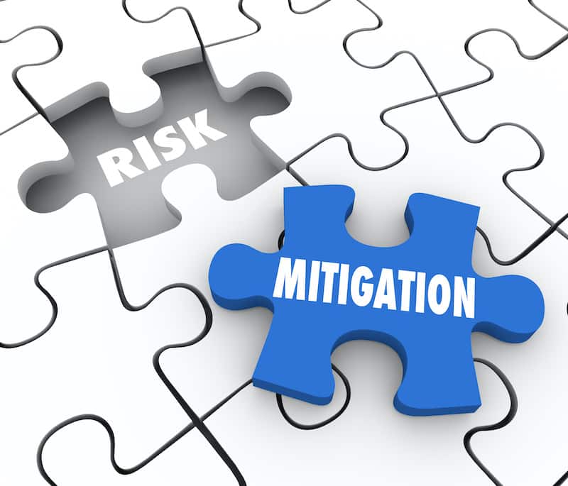 Risk Mitigation words on puzzle pieces to illustrate reducing problems, trouble, dangers or hazards and increase security and protection from harm
