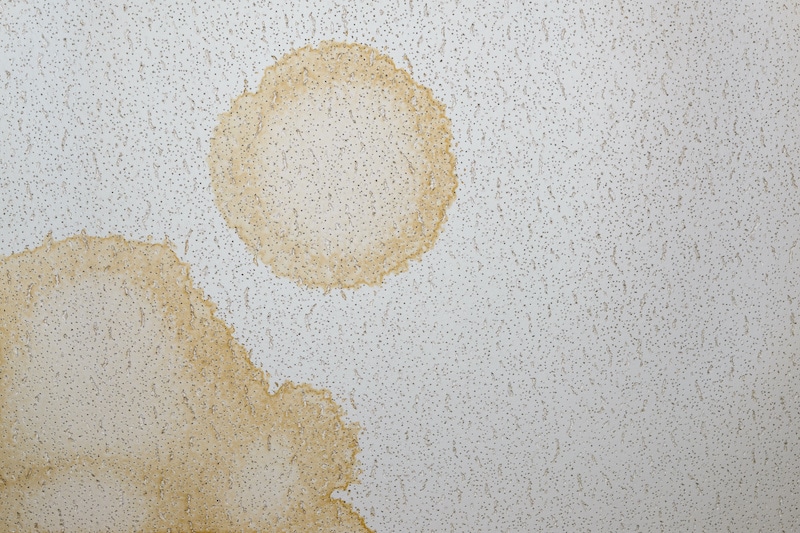 Looking directly up at a dirty stained ceiling tile. Stained were made by water leaking from above.
