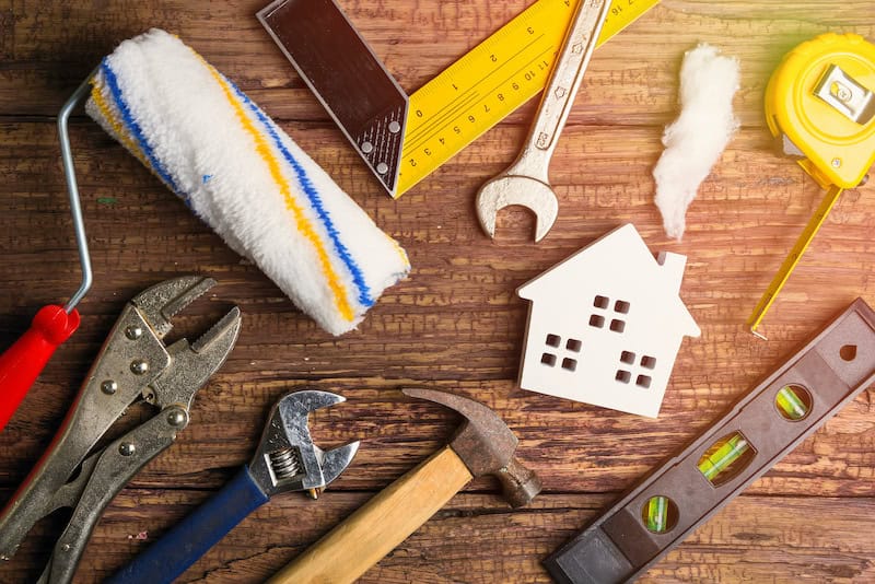 Wooden white house toy and construction tools on wooden background with copy space.Real estate concept, New house concept, Finance loan business concept, Repair maintenance concept