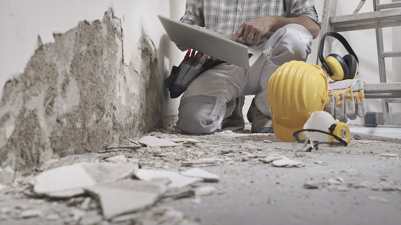 house renovation concept, construction worker use computer, protective construction work tools, helmet, yellow headphones and glasses in background