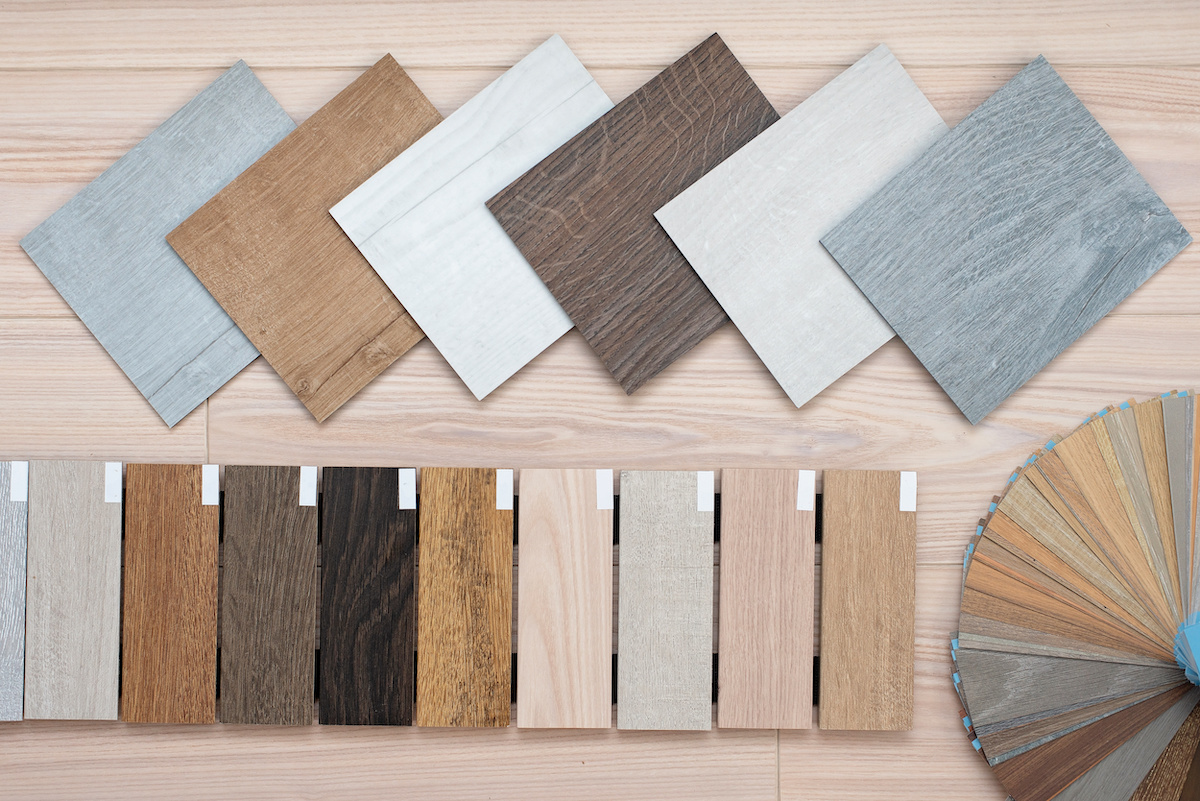 An example of a catalog of luxury vinyl floor tiles and a designer palette with textures with a new interior design for a house or floor on a light wooden background.