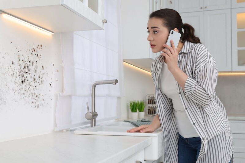 Woman talking on phone and looking at wall in kitchen