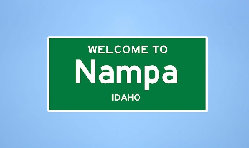 Isolated US city limit sign of Nampa, located in Canyon county, Idaho. Place name sign from the USA on blue background.