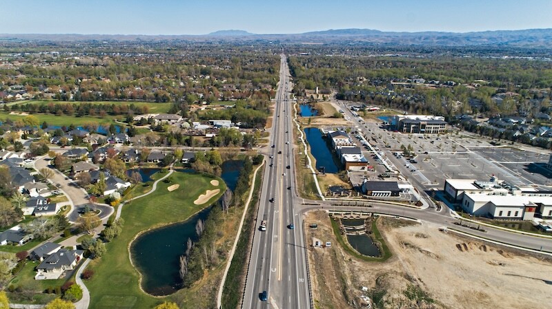 Drone aerial view of Eagle, Idaho looking toward mountains with an empty shopping center and parking lot