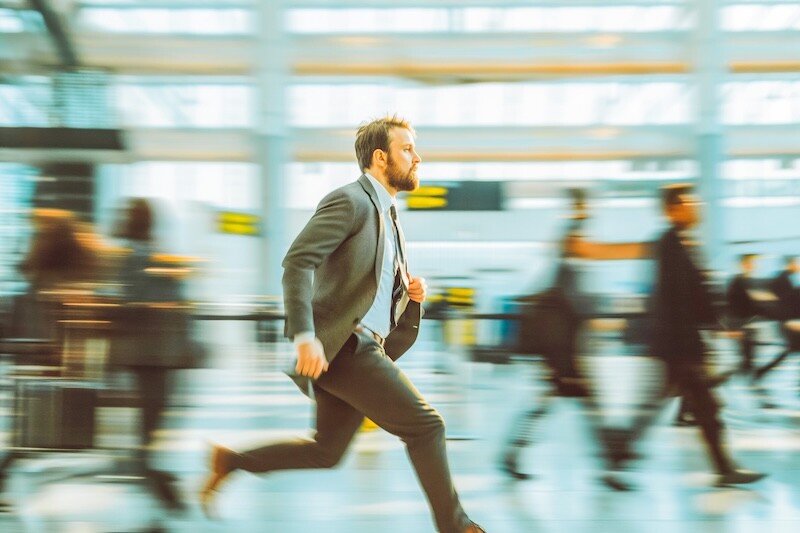 Handsome businessman rushing in airport to catch a flight with blurry people around him.