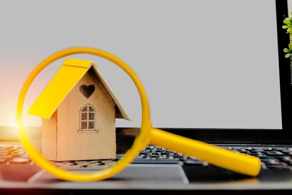 Searching home Buy and sell concept. Model houses that are placed on notebooks and have glasses sold as front scenes. The background is a computer screen with free space to enter advertising messages.