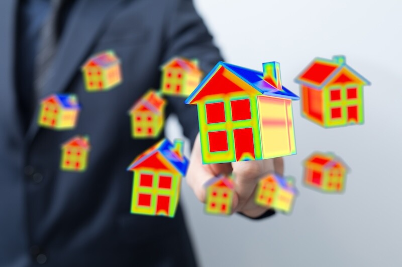 Businessman Displaying Thermal Houses for Real Estate Investment Concept
