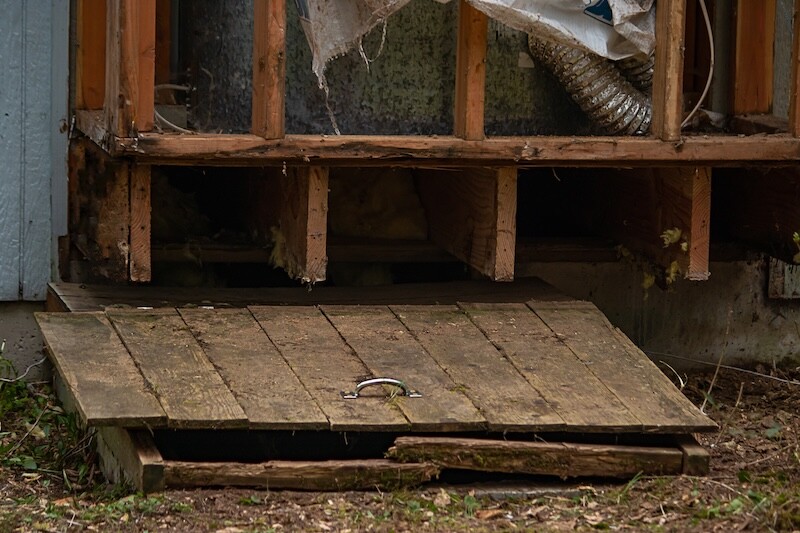 old wooden hatch to crawlspace damaged and worn with age