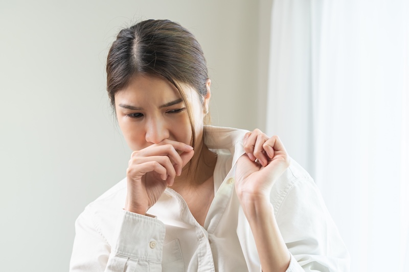 Bad smell nose concept asian young housewife woman having smelling clothes her shirt collar, sniff smelly dirty stinky musty, look disgusting from clothes after washed, laundry out of machine at home.