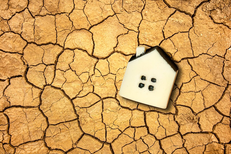 Global warming and climate changing concept with a little toy house on the dried soil.