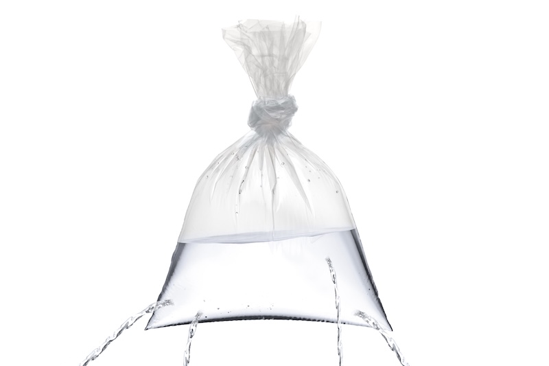 A plastic bag with holes, being filled, but the water is leaking out the holes isolated on white background