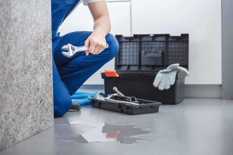 Cropped photo of a plumber with a wrench repairing leakage