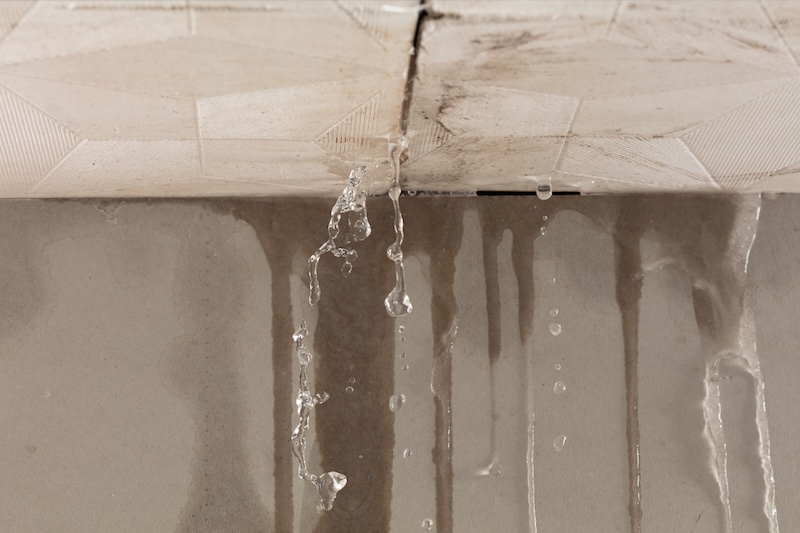 Heavy storm rain create water flow from edge of ceiling and dirty stain on wall. Water leaking from top ceiling as droplets and flow in old house