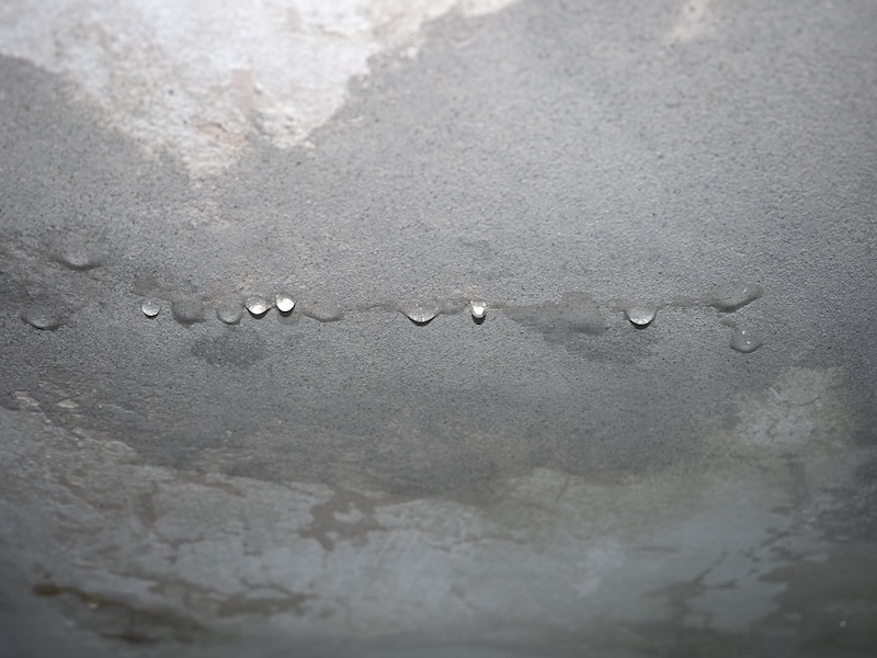 damage caused by dampness and moisture on a ceiling, with droplets of water infiltration