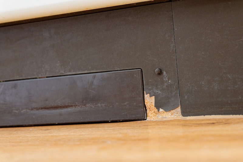 Closeup of swollen wooden floor and damaged kitchen baseboard caused by water leakage. Ideal for concepts of home repair, renovation, insurance claims or property maintenance. Holgers.pictures (c) Holger Iggena